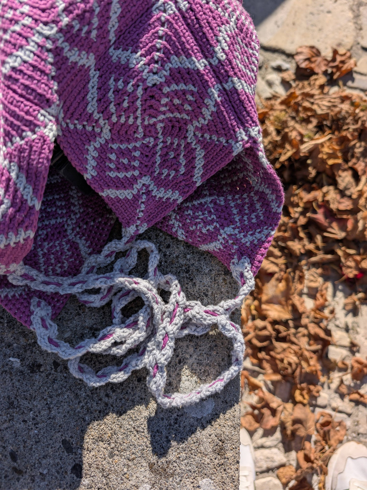 Pimlico bag on a stone ledge, the twisted cord strap coiled in front