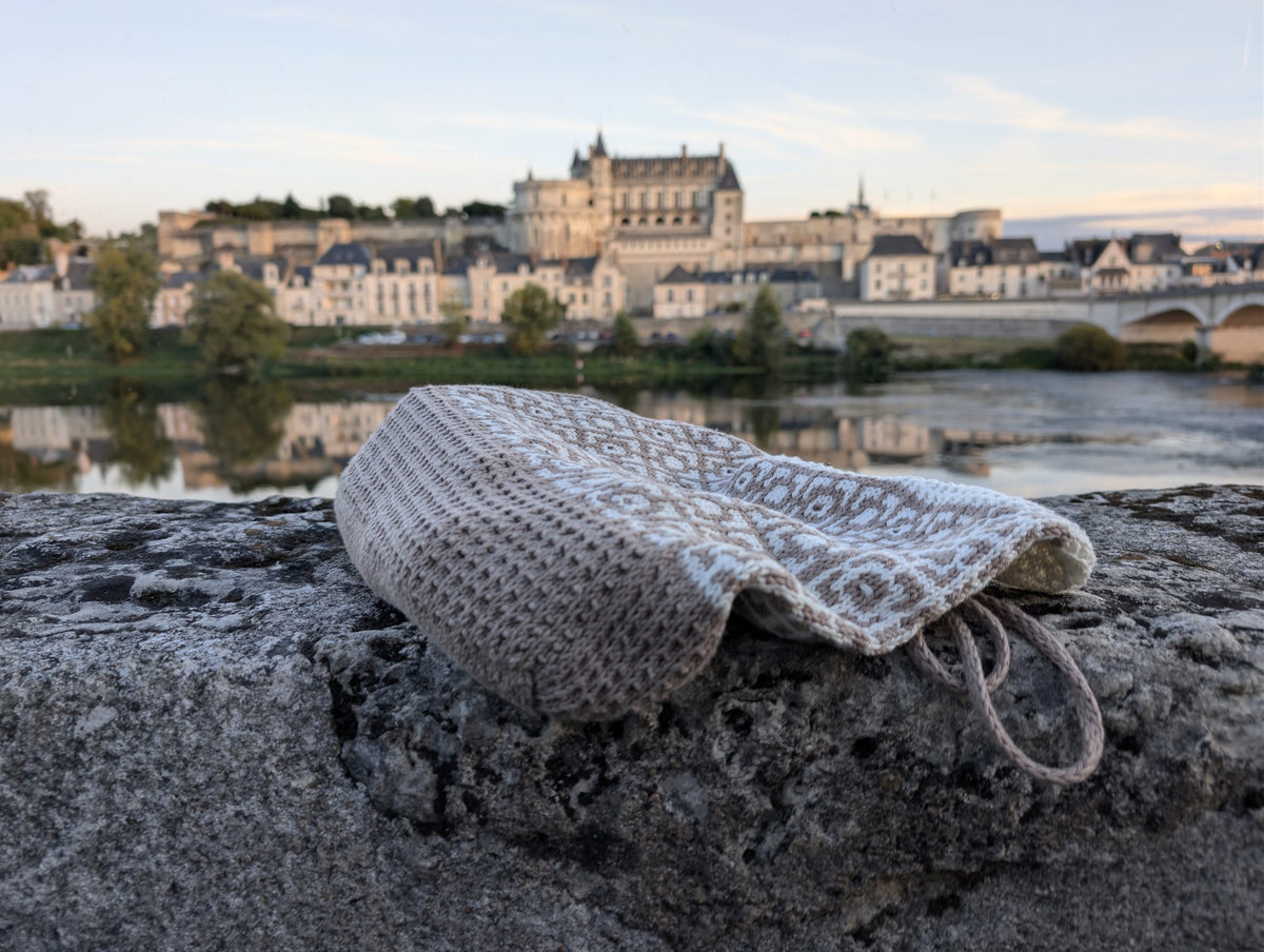 Cairo mosaic tote bag in taupe and cream resting on a stone wall by a chateau