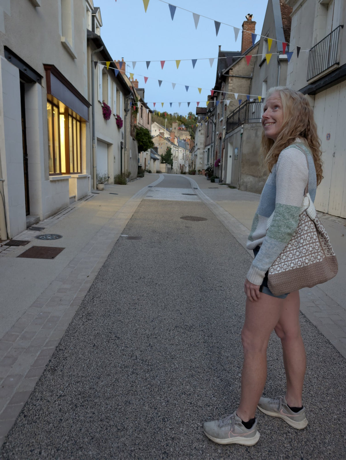 Full-length view of the Cairo knitted tote bag worn in a village street