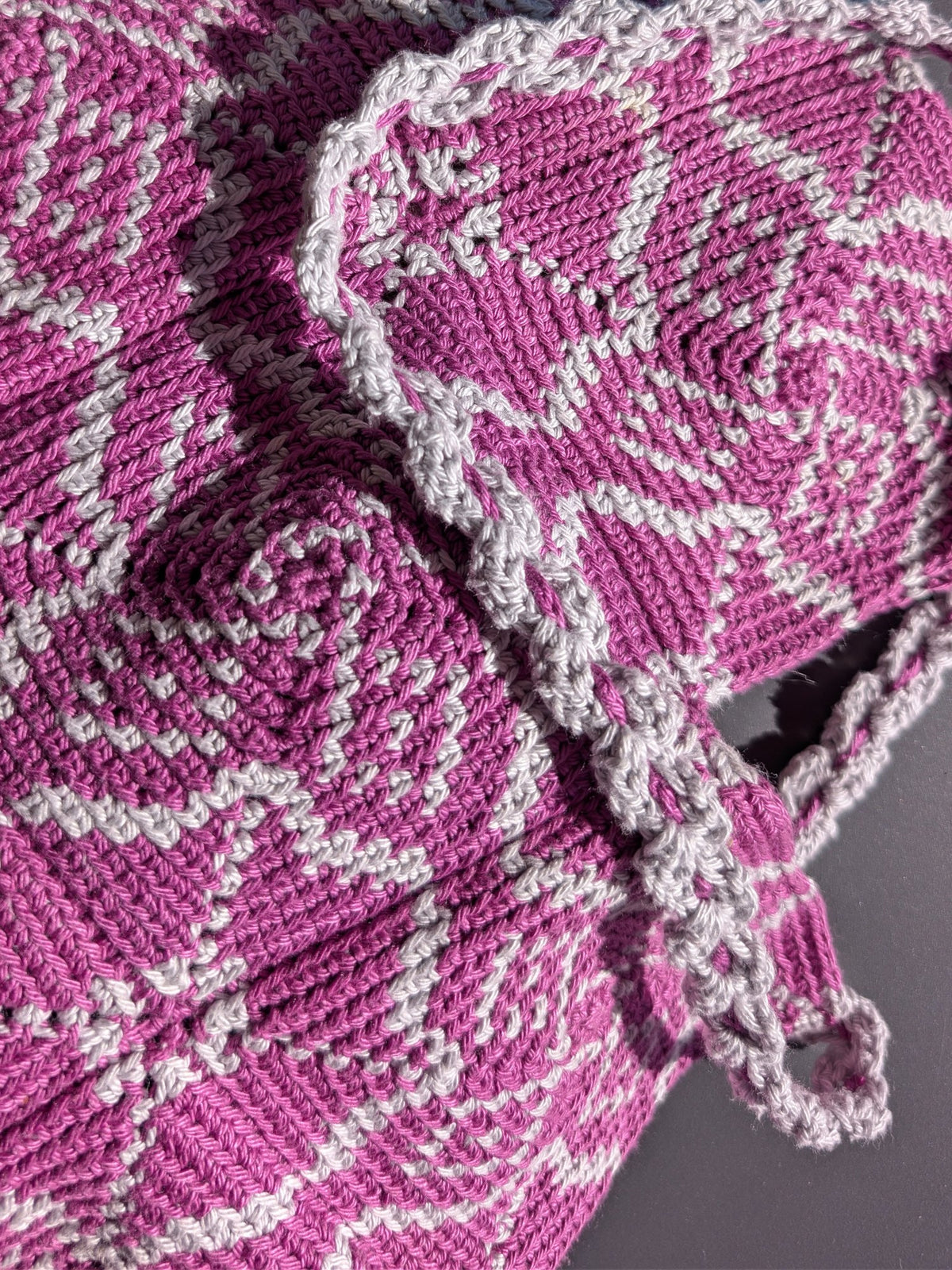 Pimlico bag lying flat, the cord strap looped across the magenta and pale grey pattern